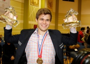 A Triumphant Magnus Carlsen holding the trophies for the Worl;d Blitz and Rapid Chess Championships. source:http://dubai2014wrb.com/en/